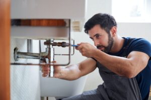 male-plumber-using-wrench-to-fix-leaking-sink-in-home-bathroom.jpg